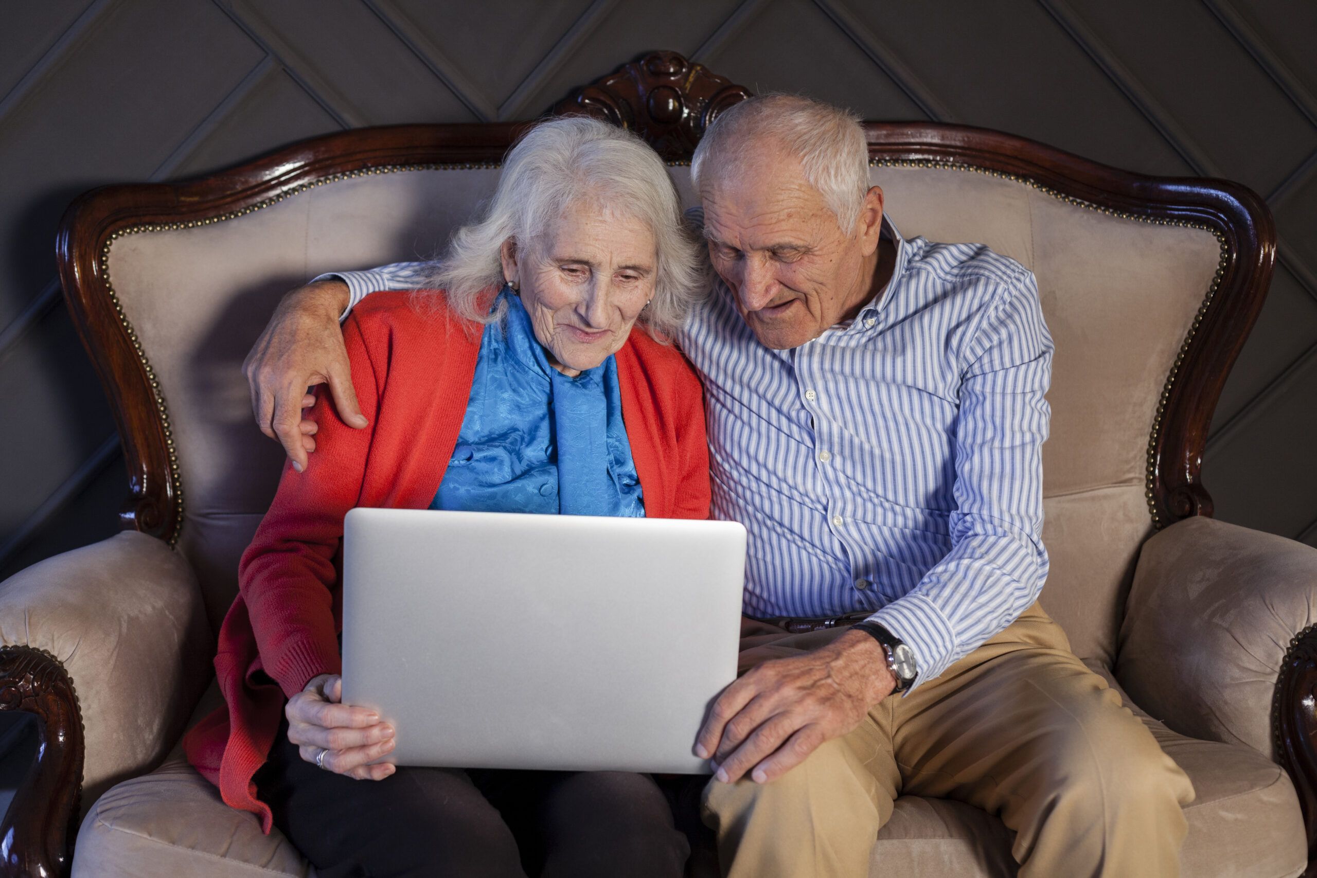 elderly couple holding laptop together scaled